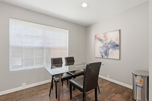 Une salle de réunion avec une table en verre, des fauteuils en cuir, un tableau accroché au mur et une poubelle.