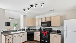 A modern kitchen with light wood cabinets, a black stove, a microwave, and a white refrigerator. - Luxe 3B 5B Cozy, Spacious Home, 5-star Stay in Frisco (Frisco)