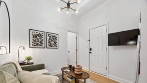A modern living room with a sofa, a coffee table, and framed artwork on the wall. - 2BR 2BA in Historic Brownstone Near Subway (New York)