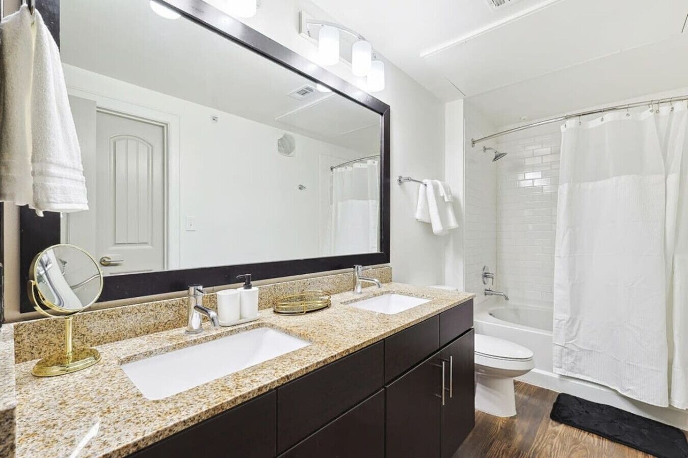 A modern bathroom with two sinks, a large mirror, and a shower area.