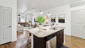 A modern kitchen with a granite countertop, stainless steel appliances, and pendant lighting. - Luxurious 2b2b Near Toyota HQ, The Star, Legacy West (Frisco)
