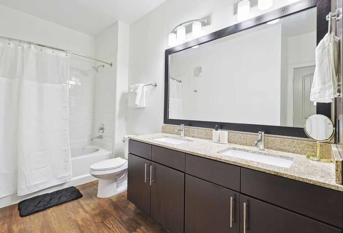 A modern bathroom with a bathtub, toilet, and vanity with a mirror.