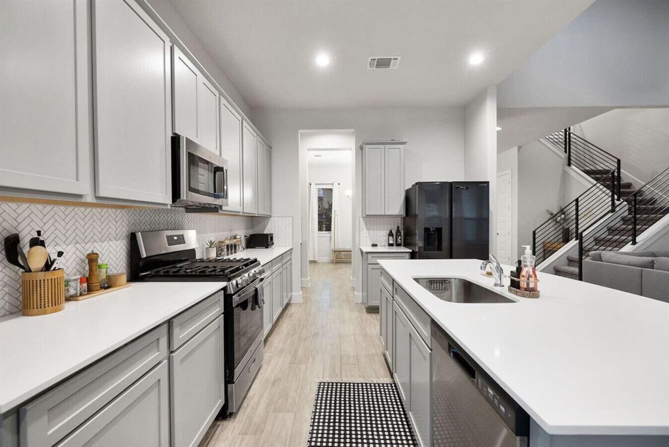 A modern kitchen with white cabinetry, stainless steel appliances, and a central island.