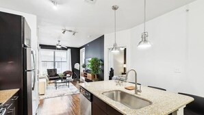 Una cocina moderna con encimeras de granito, electrodomésticos de acero inoxidable e iluminación colgante.