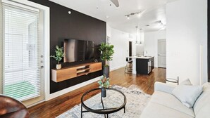 Una sala de estar moderna con un televisor de pantalla plana, una unidad de entretenimiento de madera y un ventilador de techo.