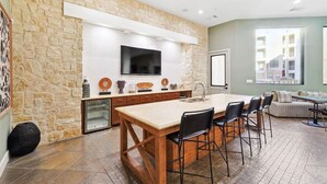 Una cocina amplia con una isla grande, pared de piedra y un televisor de pantalla plana.