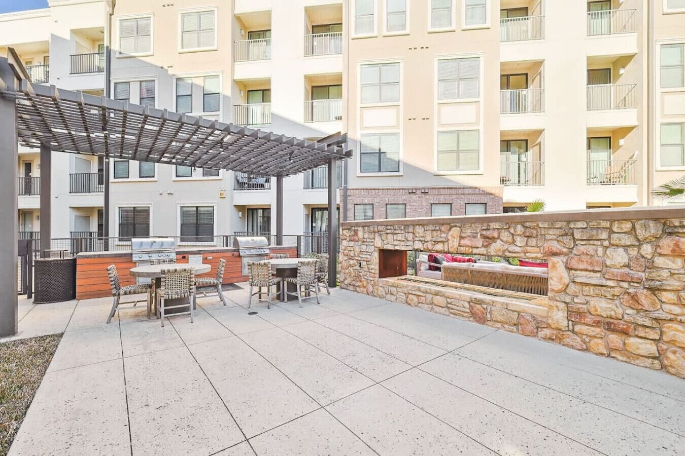 Un patio al aire libre con una parrilla, zona de estar y pared de piedra.