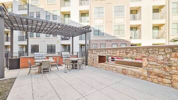 Un patio al aire libre con una parrilla, zona de estar y pared de piedra.