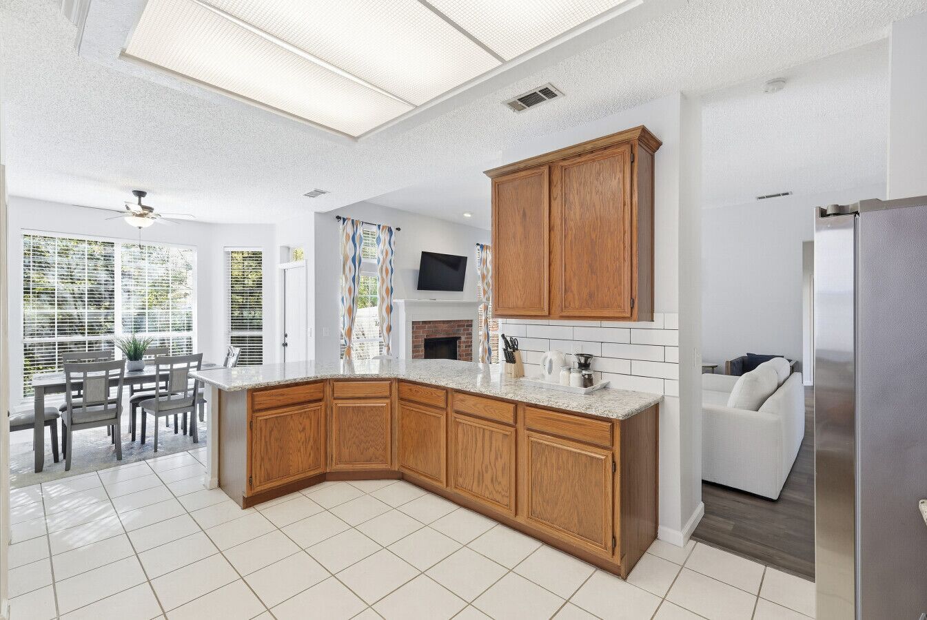 A modern kitchen with wooden cabinets, a built-in oven, and a dining area with a table and chairs.
