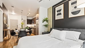 Une chambre d’hôtel moderne dotée d’un grand lit, d’un coin repas et d’une kitchenette.
