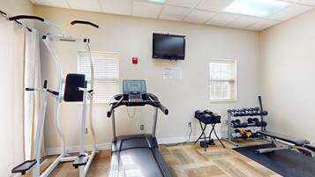 A gym with treadmills, a stationary bike, dumbbells, and a bench.