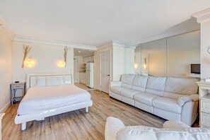 A bedroom with a bed, a white sofa, and a large mirror. - Daytona Beach Resort 719 (Daytona Beach)