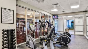 Ein Fitnessstudio mit Laufbändern, Crosstrainern und einem an der Wand befestigten Fernseher.