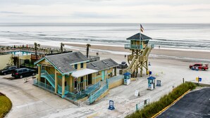 A lifeguard tower, beach safety building, and parking area at a beach. - Pirates Cove 618 - Sunshine Serenity (Daytona Beach Shores)