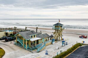 Ein Rettungsschwimmturm, ein Gebäude für Strandaufsicht und ein Parkplatz am Strand.