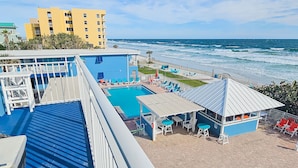 A rooftop pool area with a view of the ocean, a small bar, and lounge chairs. - Coconut Palms Beach Resort 4312 (New Smyrna Beach)