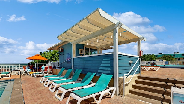 A poolside area with lounge chairs and a covered seating area. - Coconut Palms Beach Resort 4312 (New Smyrna Beach)