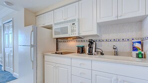 Una cucina con mobili bianchi, un forno a microonde, una macchina da caffè e un lavandino.