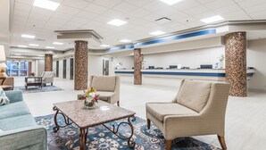 Un'ampia hall con reception, comodi posti a sedere e colonne decorative.