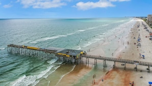 A pier extending into the ocean with a beach on one side.