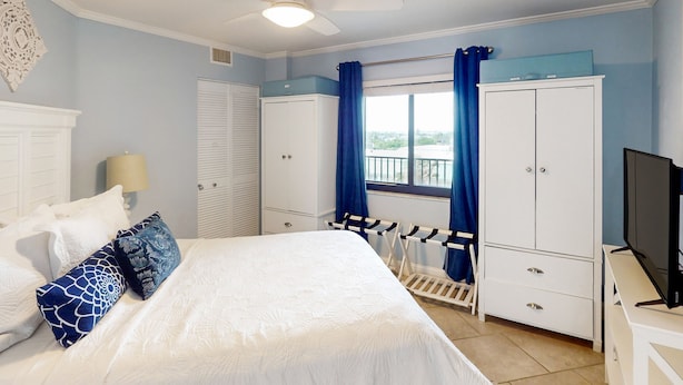 A bedroom with a bed, white wardrobe, and a television.