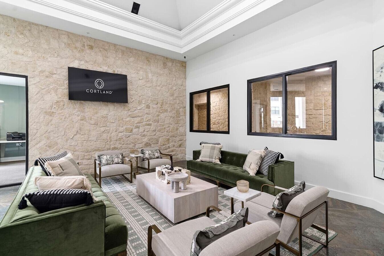 A modern living room with a stone accent wall, a sign reading "CORTLAND", and a large window with a view.