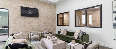 A modern living room with a stone accent wall, a sign reading "CORTLAND", and a large window with a view.
