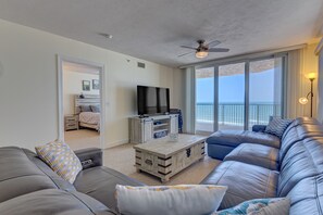 A modern living room with a grey leather sofa, a wooden coffee table, and a flat-screen TV.