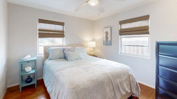 Un dormitorio con cama, mesita de noche, cómoda y ventilador de techo.