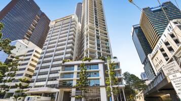 A modern high-rise building with a glass facade, multiple balconies, and a sign for 'Maurice Blackburn Lawyers' at the ground level.