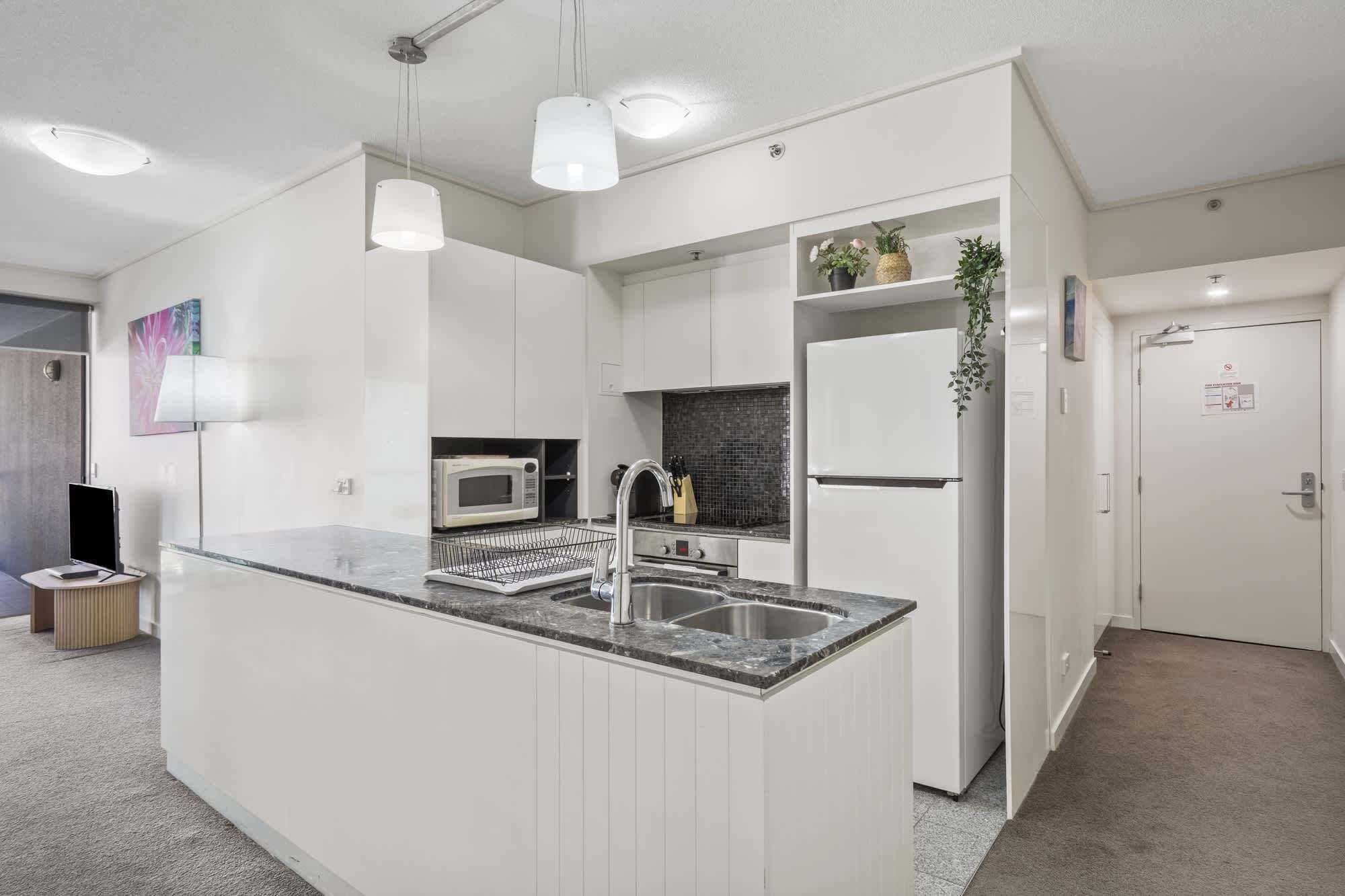 A modern kitchen with a central island, built-in microwave, and stainless steel appliances.