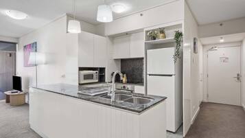 A modern kitchen with a central island, built-in microwave, and stainless steel appliances.