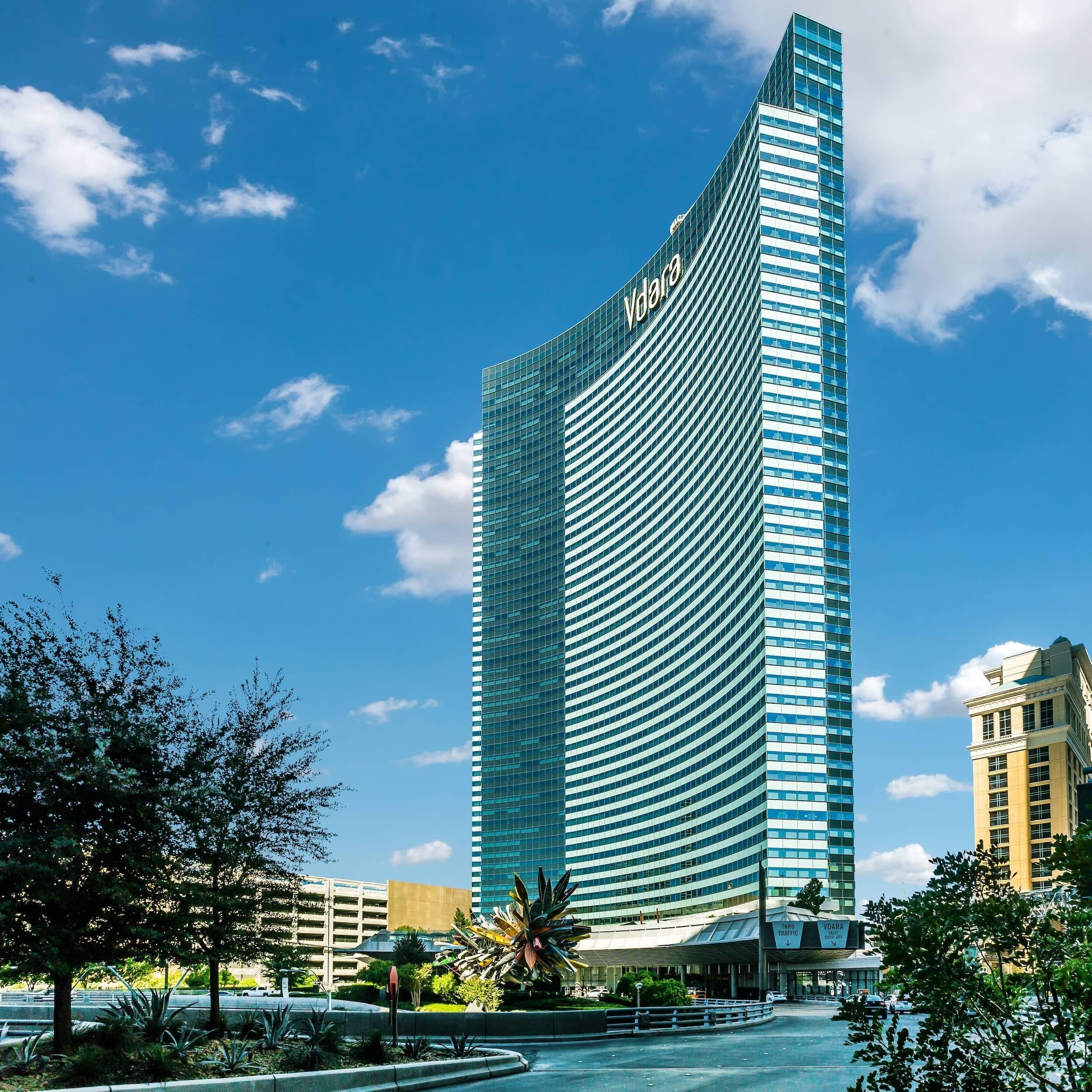 A tall, modern hotel with a curved facade and a prominent 'Vodafone' sign.