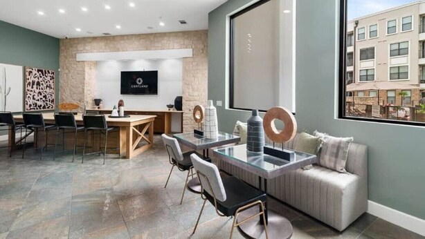 A modern interior with a dining area, a sofa, and a large window offering a view of buildings. - Great for Children 2 Bedroom With Bunk Beds (Frisco)
