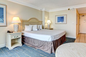 Ein Hotelzimmer mit einem großen Bett, zwei Nachttischen inklusive Lampen, einem Beistelltisch mit Telefon und einem kleinen Tisch mit Stuhl.