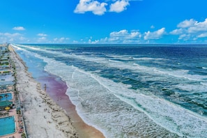 Ein Strand mit Schwimmbecken und Liegestühlen.