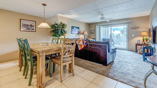 A dining area with a wooden table and chairs, a sofa, and a TV. - Twenty-six Twenty-six 202 - Shores Delight (Daytona Beach)
