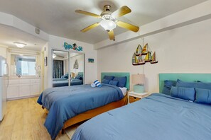 Ein Schlafzimmer mit zwei Betten, einem Deckenventilator, einem Spiegel und einer Wand mit Bootsdekorationen.