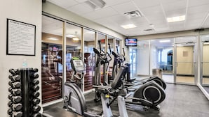 Een fitnessruimte met cardioapparatuur, gewichten en een loopband.