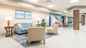 A spacious lobby with a blue sofa, beige armchairs, a patterned rug, and two lamps. - Daytona Beach Resort 1404 (Daytona Beach)