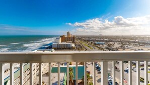 A coastal cityscape with a view of the ocean, a hotel with a pool, and a parking lot. - Daytona Beach Resort 1404 (Daytona Beach)