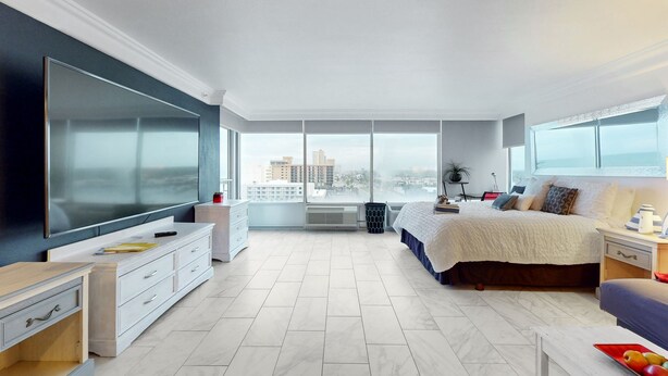 A modern bedroom with a large bed, a TV, and a city view. - Daytona Beach Resort 801 (Daytona Beach)