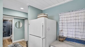 A kitchen with a white refrigerator, a marble countertop, and a blue tiled backsplash.