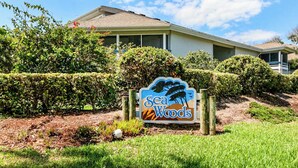 A sign for Sea Woods with a house in the background. - Sea Woods Villa 4412 - Villa at New Smyrna Beach (New Smyrna Beach)