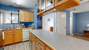 A kitchen with wooden cabinets, a granite countertop, and a built-in oven. - Sea Woods Villa 4412 - Villa at New Smyrna Beach (New Smyrna Beach)