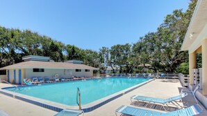 A swimming pool with lounge chairs and a building with a tiled roof. - Sea Woods Condo 131 - Coastal Hide Away (New Smyrna Beach)