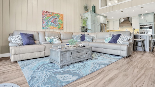A spacious living room with a sectional sofa, a coffee table, and a colorful abstract painting. - Sea Dunes A1- Dream Catcher (New Smyrna Beach)