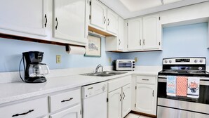 Una cocina con armarios blancos, una cafetera, un tostador y un horno.
