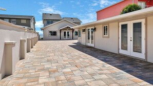 A residential area with a paved walkway leading to a house with a garage door. - Atlantic Sunrise Home (Daytona Beach Shores)
