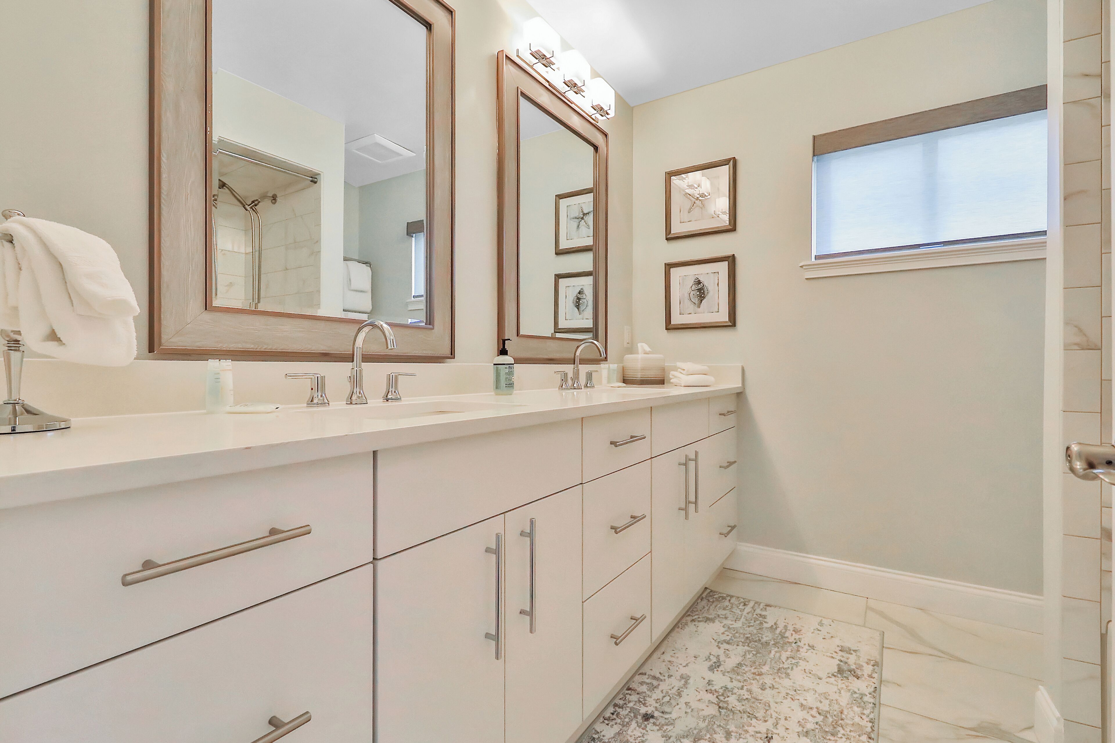 A bathroom with a large mirror, white vanity, and a shower area.